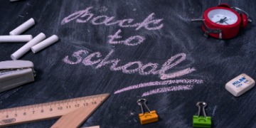 Schulstart Tafel mit verschiedenen darauf abgelegten Gegenständen und der Aufschrift "back to school"